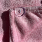 A close-up of the pink microfibre hair wrap, folded over to show a small, clear oval button closure.