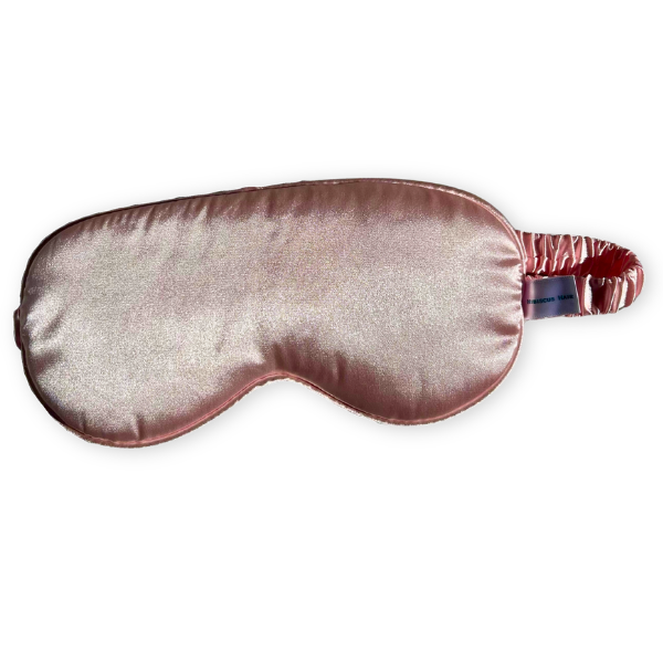 A satin sleep mask in a dusty rose with a matching elastic strap, shown against a plain white background.